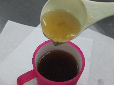カップにに入ったお茶に蜂蜜入れる写真