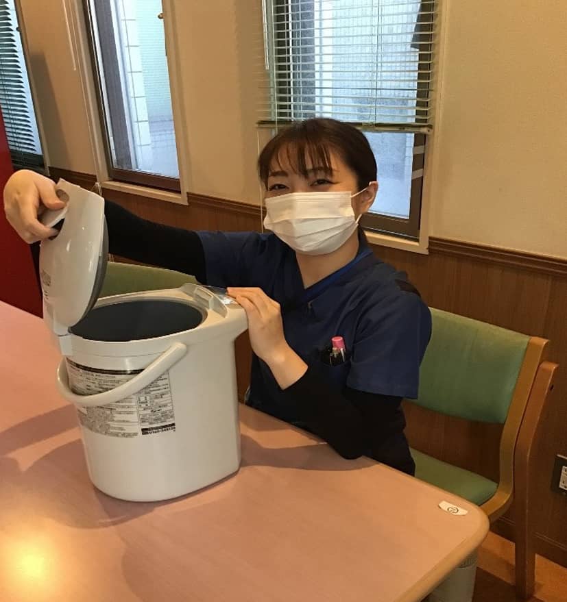 女性が水を注ぐためにポットの蓋をあける写真