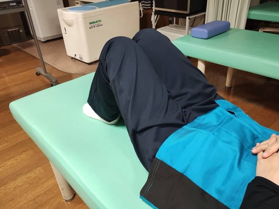 膝を立てて片足を片側に倒すトレーニングの様子1